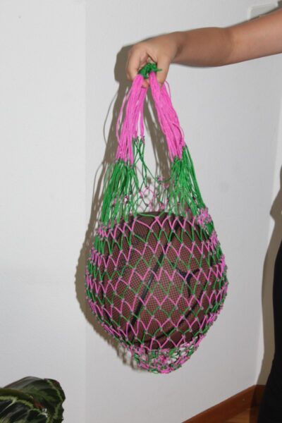 Un enfant transporte son ballon de basket dans un filet rose et vert.